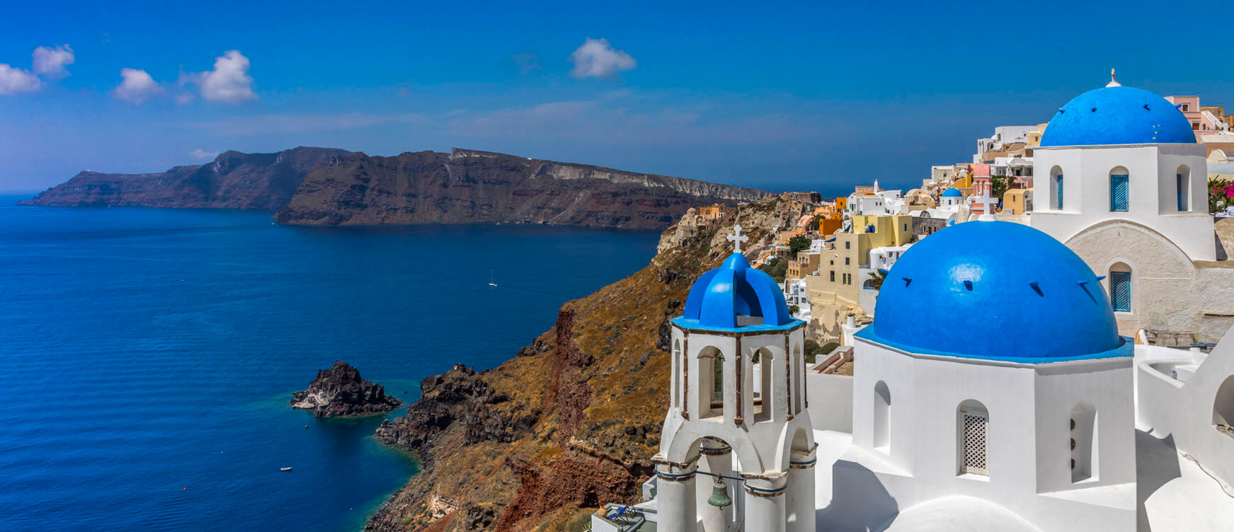 Bleu-domed églises et blanc maisons sur Santorini's caldera rim au-dessus du profonde Aegean Mer